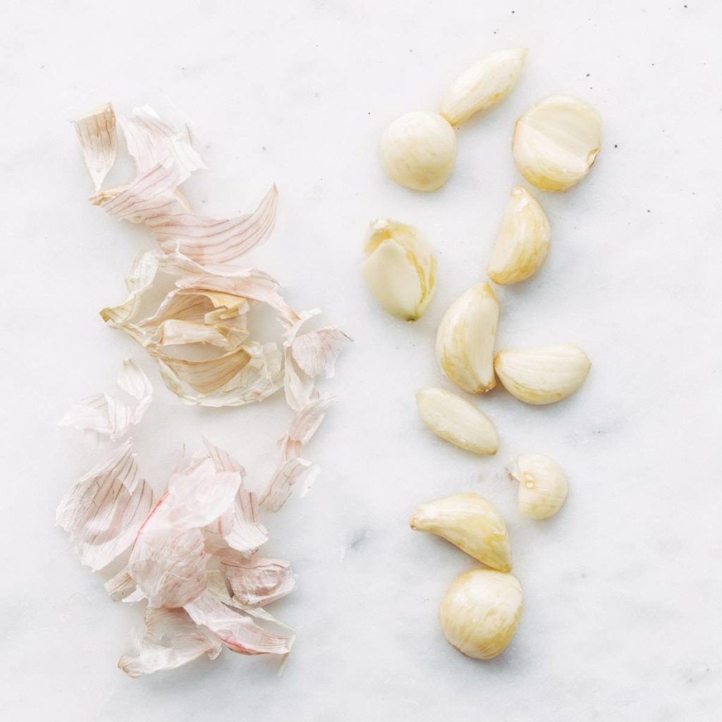 A photograph of peeled garlic cloves and their skins.