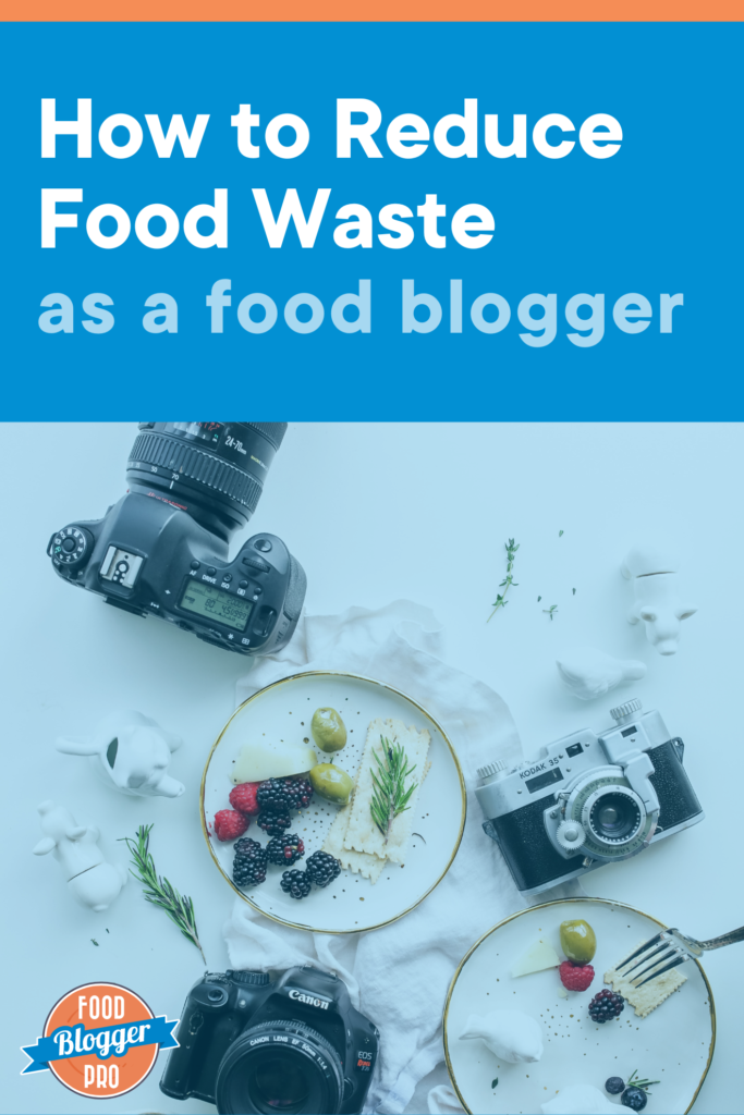 Overhead photograph of three cameras and two plates filled with berries, cheese, olives, herbs, and crackers. The image reads "how to reduce food waste as a food blogger" and has the Food Blogger Pro logo in the bottom left corner.
