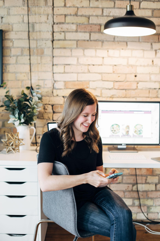 Woman scrolling on phone sitting at a desk
